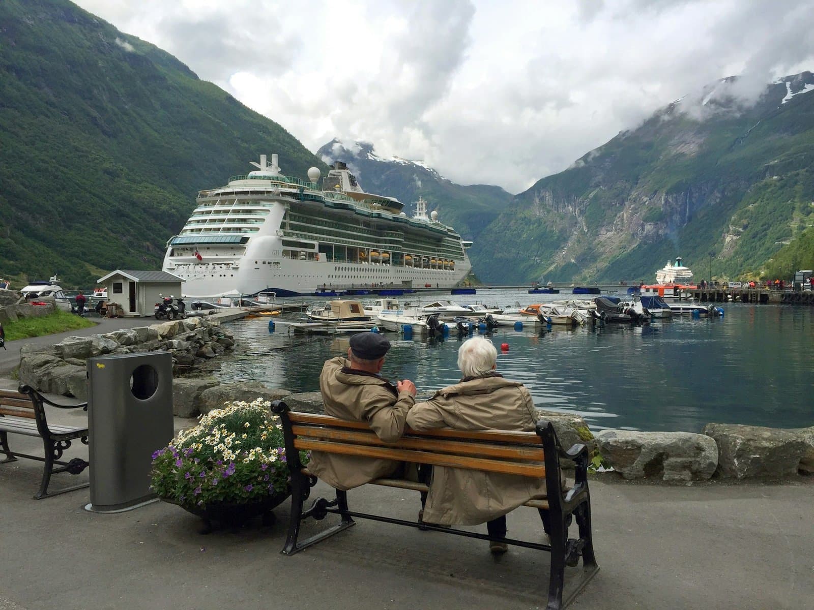 Two elderly couples at the sea side staring a boat