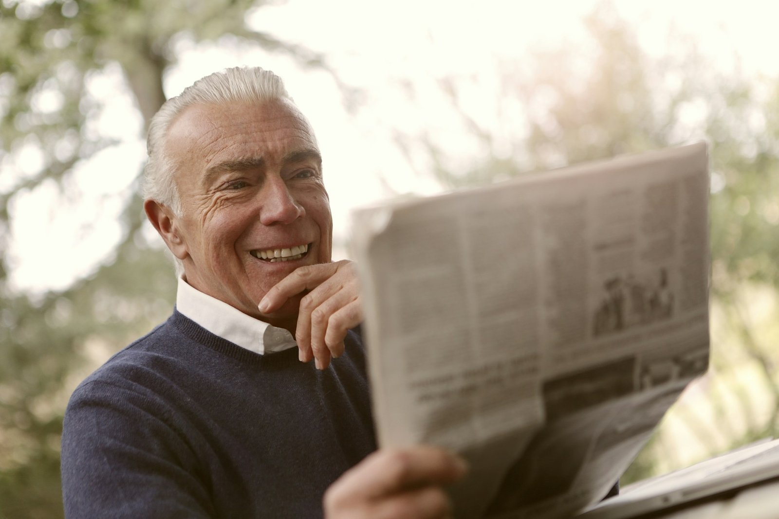 old man smiling to newspaper
